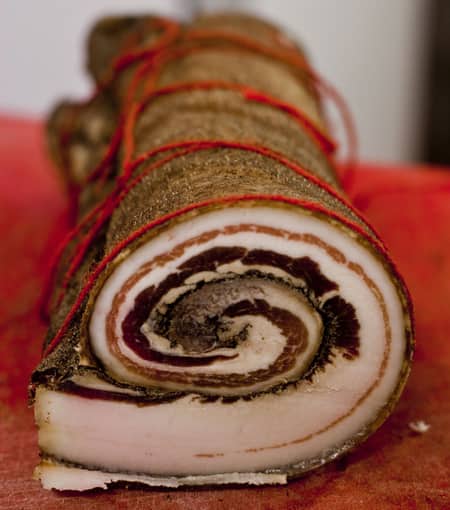A closeup view of a rolled and seasoned meat dish, tied with string and ready to cook.