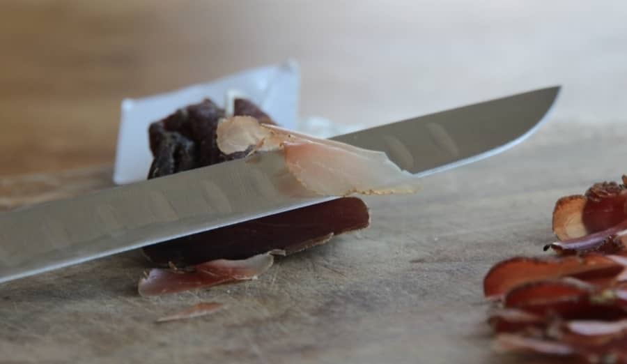 Thinly Cut Cured Meat with a prosciutto knife in the foreground.