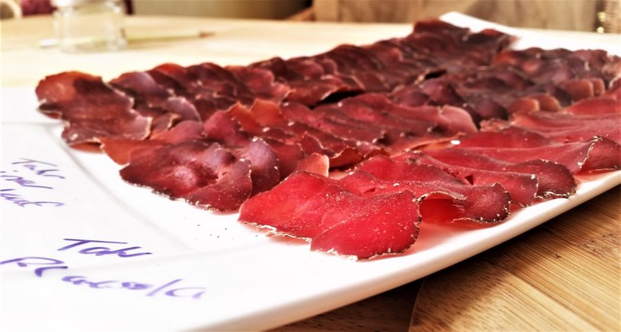 A platter of thinly sliced dry-cured ham, presented on a white serving dish, ready for an appetizing start to a meal.