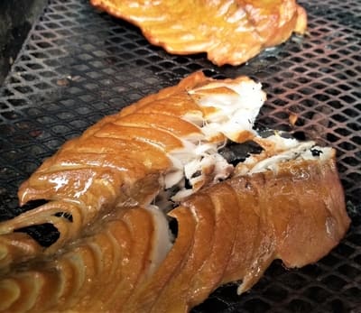 Freshly grilled fish fillets with golden, crispy skin on a mesh cooking grate.