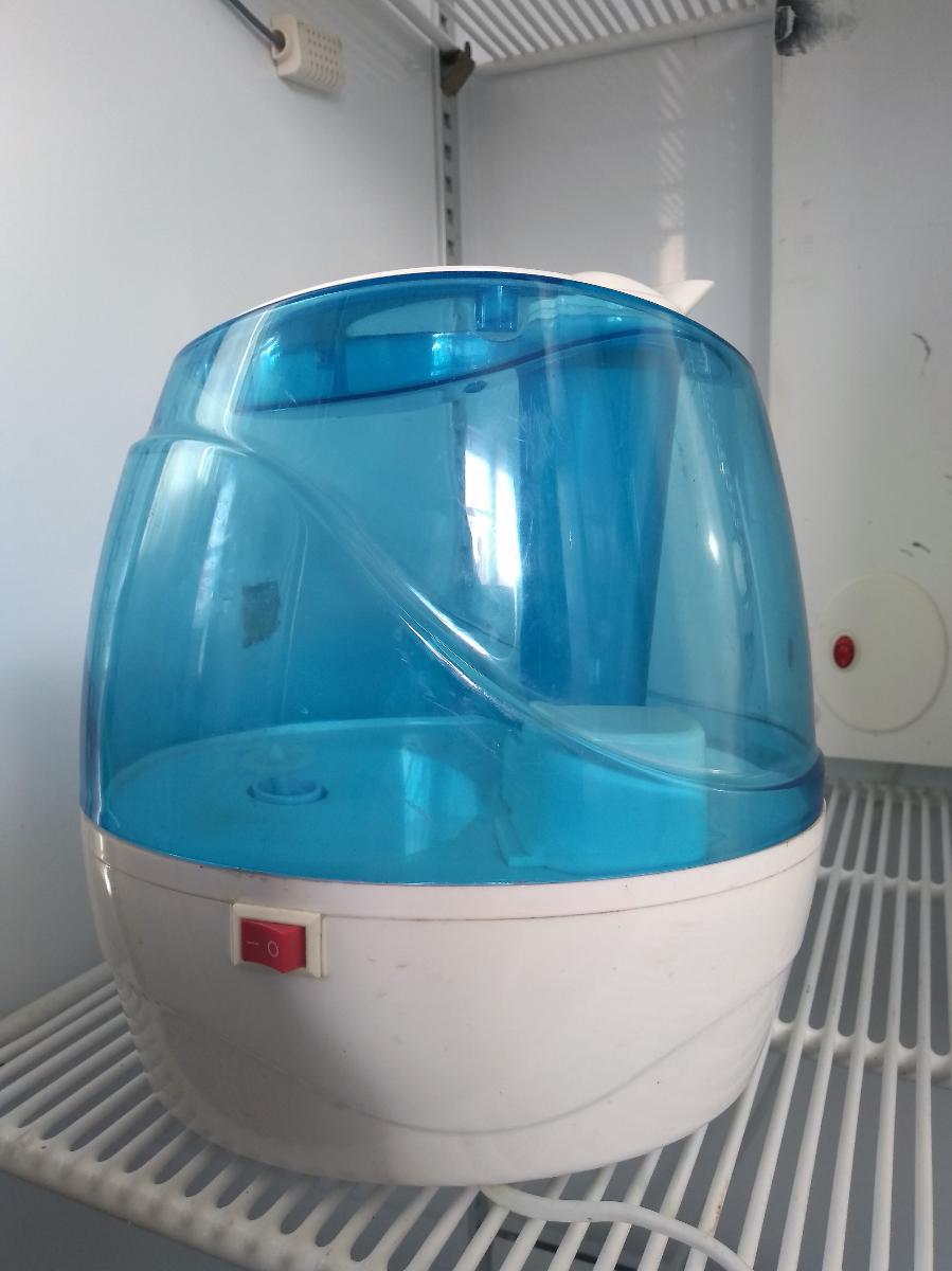 A blue and white eggshaped appliance, possibly a humidifier, sitting on a shelf inside an open drying cabinet.