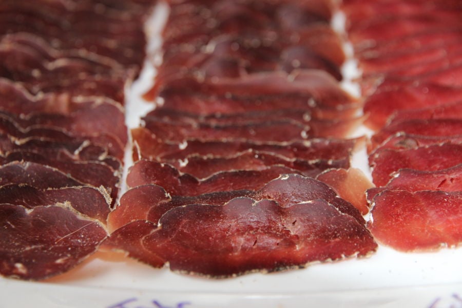 Thinly sliced dry cured venison meat layed out on a plate.