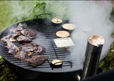 Grilling in action: smoke rises as a variety of meats and vegetables are cold smoked