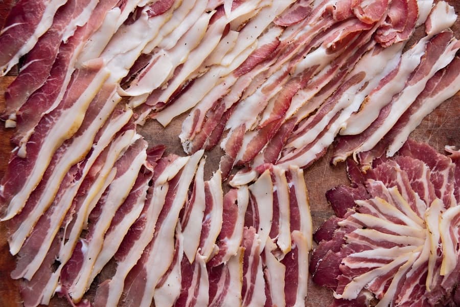 Thinly sliced cured meats arranged on a wooden cutting board.