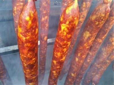 Cured sausages hanging to dry, showcasing a rich, marbled appearance.