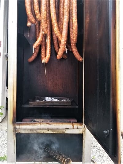 Sausages hanging in a smokehouse, being infused with a rich, smoky flavor.