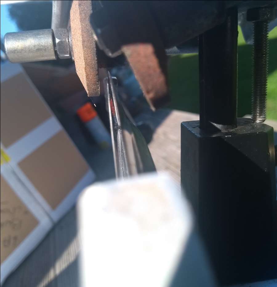 Meat Slicer Sharpener close up along blade with sharpener in background.