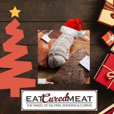 A festive holiday-themed image featuring a brochure or book titled "Meat Curing: The Magic of Salting, Smoking & Curing", with a picture of cured meats on its cover, surrounded by