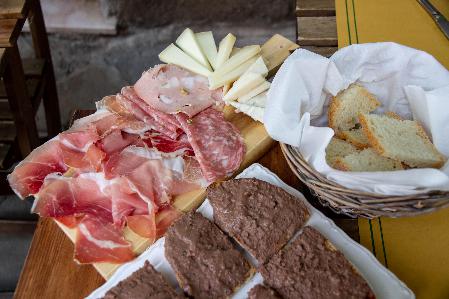 A delightful assortment of italian cold cuts, cheese slices, crusty bread, and pâté served on wooden boards and in baskets, ready for a savory feast.