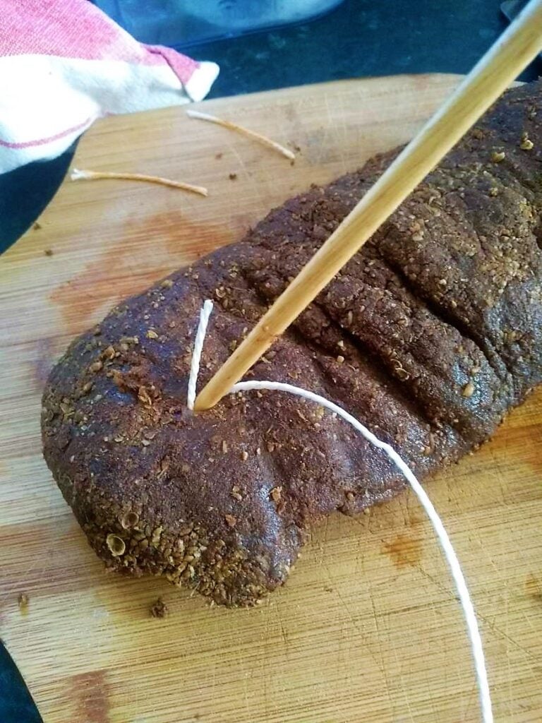 Slicing homemade bread on a wooden cutting board with a bread knife.