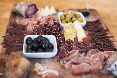 An appetizing charcuterie board featuring an assortment of cured meats, olives, cheese, and crackers, artistically arranged on a rustic wooden platter.