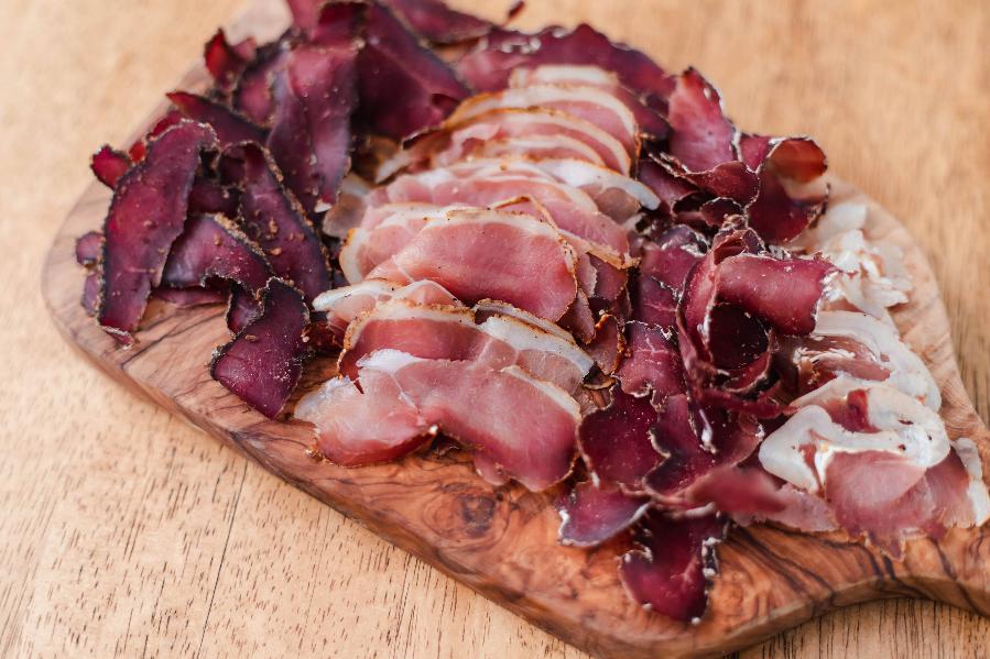 Slices of assorted cured meats arranged on a wooden serving board.