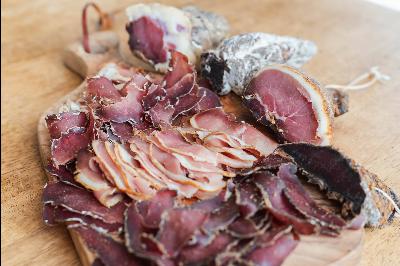 Sliced cured meats arranged on a wooden cutting board, showcasing a variety of textures and colors from the different cuts.