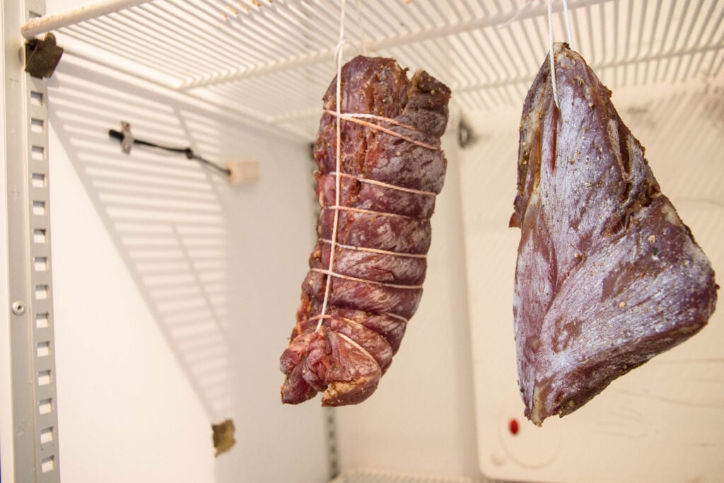 Craft cured meats hanging to dry in a controlled aging environment.