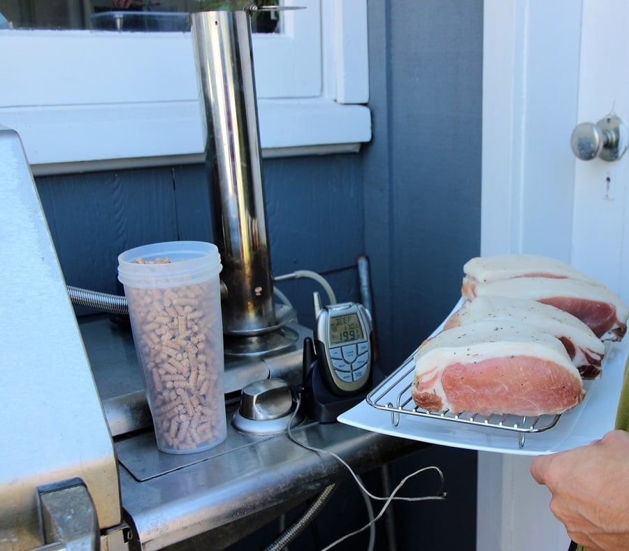 Preparing for a barbecue: a tray of salt cured meat ready to be smoked with a thermometer on hand to ensure perfect cooking, next to a container of wood pellets for the smoker.