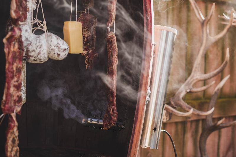 Traditional meat smoking process with various meats and sausages hanging inside a smokehouse.