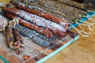 Assorted cured sausages displayed on a wooden cutting board, showcasing a variety of textures and spices, ground with a precision mincer.