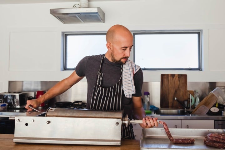 A focused chef attentively prepares salami at home, showcasing culinary expertise.