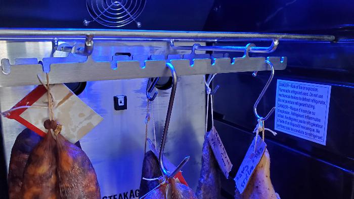 Charcuterie meats hanging inside a drying chamber with a controlled environment for the aging process.