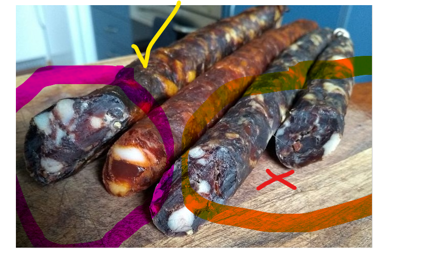 A selection of homemade, rustic, dry-cured sausages on a wooden cutting board, featuring a variety of textures and colors indicative of different spices and curing processes, ready for a gourmet tasting.