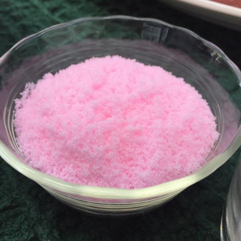 A bowl of bright pink colored granular substance, possibly a flavored salt, sugar, spice mix, or related to differences in cured and uncured meat.