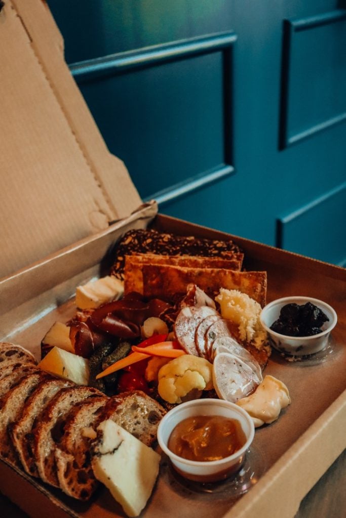 A gourmet charcuterie board essentials packed with assorted cheeses, cured meats, fruits, and crusty bread, all delicately arranged for tasteful indulgence.