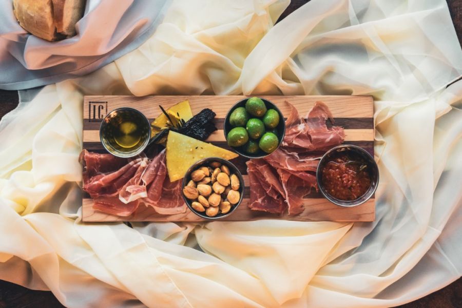 A delectable charcuterie board with an assortment of cured meats, olives, nuts, and dips, draped with a soft, textured fabric, presenting luxurious and inviting culinary ideas.