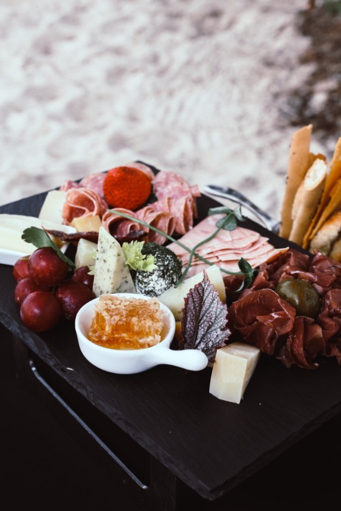 A gourmet charcuterie board with images & ideas, featuring a variety of cheeses, cured meats, fresh grapes, and honeycomb, artistically arranged for a delightful culinary experience.