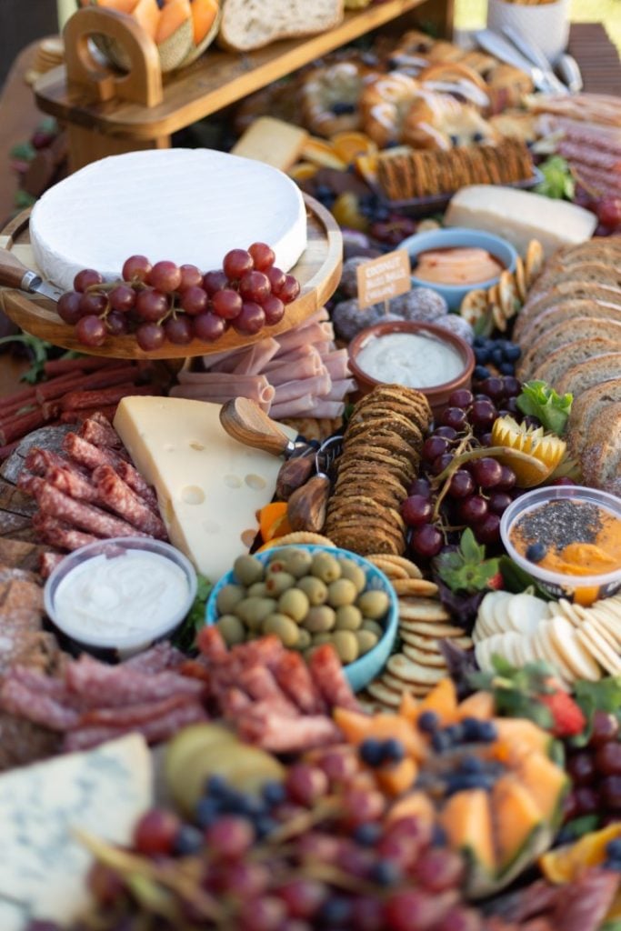 A sumptuous charcuterie board, essential for any gourmet feast or social gathering, overflowing with a variety of cheeses, cured meats, fresh fruits, olives, and assorted breads.