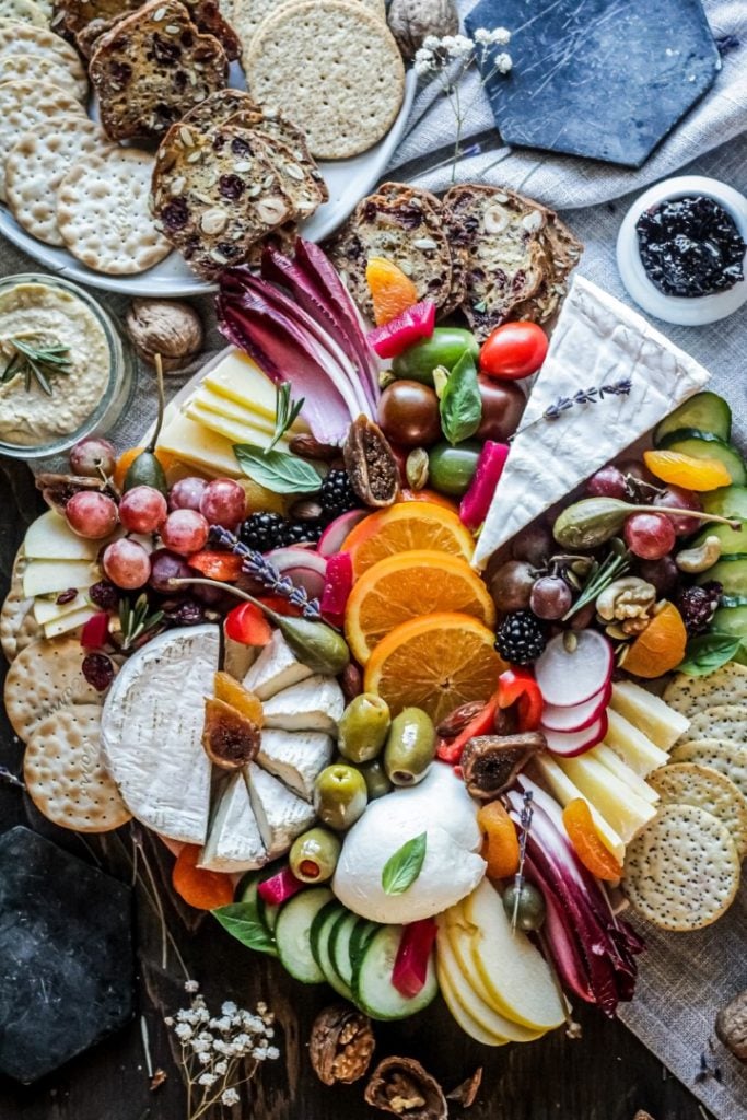 A vibrant and appetizing charcuterie board featuring an assortment of cheese, cured meat, fruit, crackers, nuts, and dips, arranged beautifully for a feast of flavors.