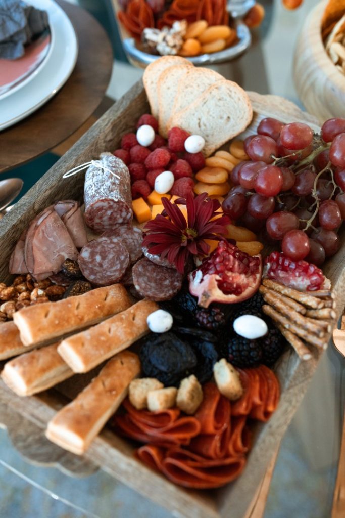 A bountiful charcuterie board filled with an assortment of cured meats, various cheeses, fresh and dried fruits, nuts, and crackers, invitingly arranged for guests to enjoy.