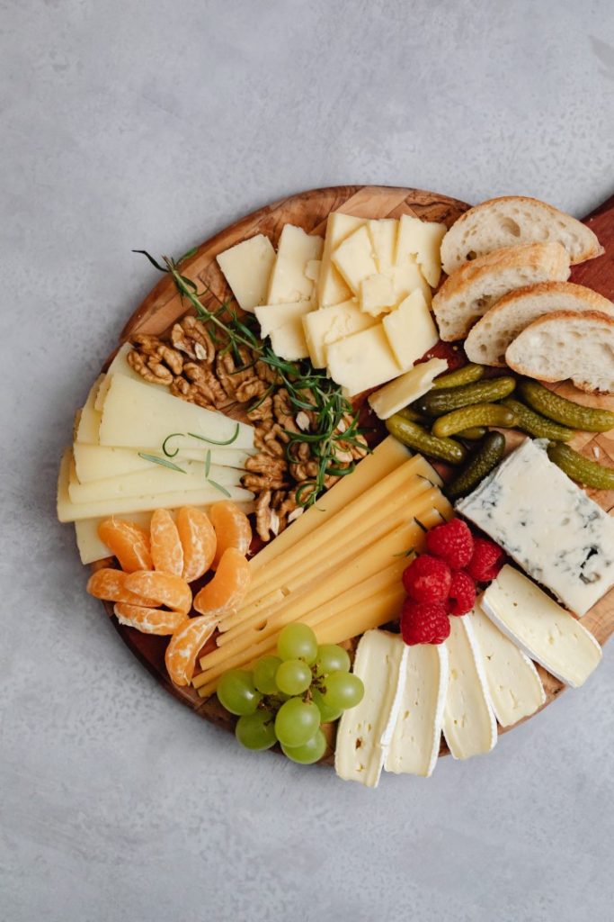 A well-arranged charcuterie board with a variety of cheeses, cured meat, crackers, nuts, and fresh fruit, presenting a delightful array of colors and textures for a gourmet snacking experience