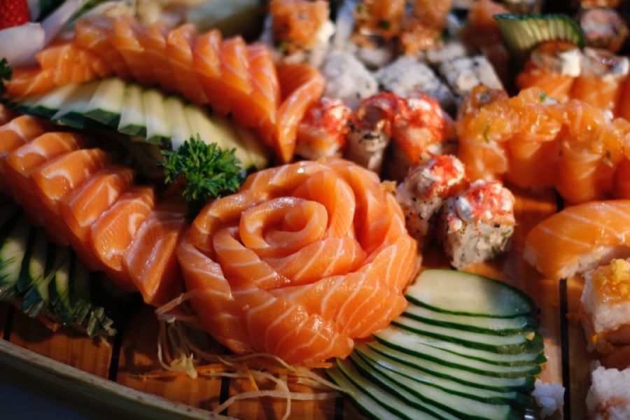 An assortment of sushi featuring elegantly arranged salmon sashimi, rolls, and nigiri, ready to delight the palate, alongside essentials from a charcuterie board.