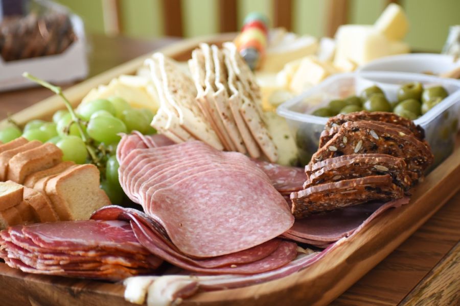 An appetizing Charcuterie Board featuring an assortment of cured meats, various cheeses, fresh grapes, bread, and crackers, perfect for a delightful gathering.