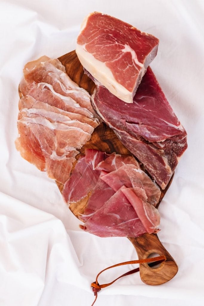 A selection of gourmet cured meats elegantly presented on a wooden cutting board.