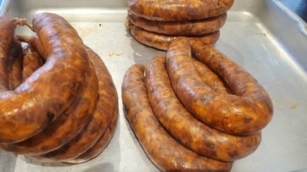 Freshly made sausages coiled on a metal tray, ready for cooking.