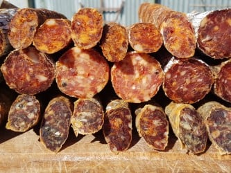 A selection of sliced cured sausages with a variety of flavors and textures, displayed prominently in the sunlight.