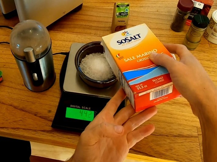 Salt being poured into a bowl which is one a digital scale for weighing the amount.